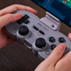 The 8BitDo SN30 Pro controller being held in two hands with a smartphone attached.